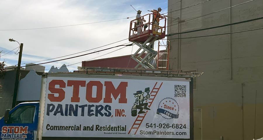 Stom Painters shown painting the exterior of a commercial building using a lift.