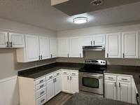 Newly painted white cabinets and sleek countertops create a bright, modern kitchen space.