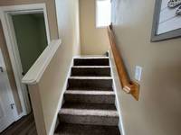 Beige walls and dark carpet create a dated, enclosed feel in the stairway.