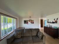 White walls and ceilings. Large windows with stained wood trim. Minimal furniture.