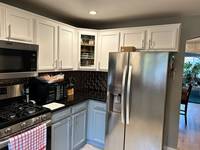 Modern kitchen interior showcasing a two-tone paint finish with white upper cabinets and soft gray lower cabinetry for a bright, cohesive look.