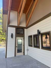 Covered entrance area with freshly painted siding, detailed trim, and preserved natural wood ceiling accents.